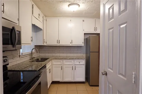 a kitchen with stainless steel appliances granite countertop a refrigerator and a stove top oven
