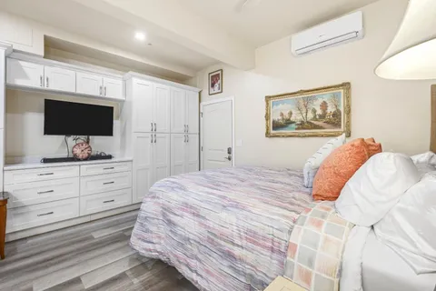 a room with stainless steel appliances kitchen island granite countertop a table chairs and a wooden floor
