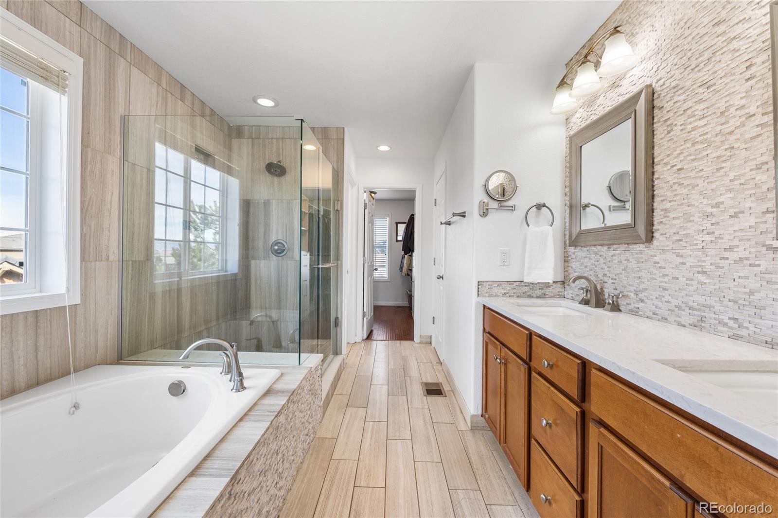 10451 Meadowleaf Way Highlands Ranch, CO 80126 - Photo 16 of 39 a spacious bathroom with a granite countertop tub a double vanity sink a mirror and a shower