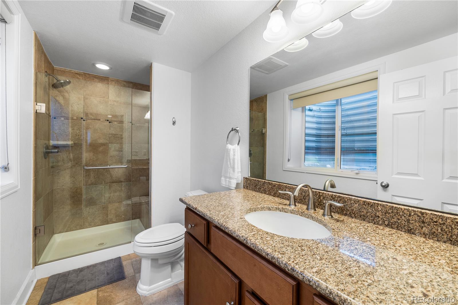10451 Meadowleaf Way Highlands Ranch, CO 80126 - Photo 27 of 39 a bathroom with a granite countertop sink toilet and shower