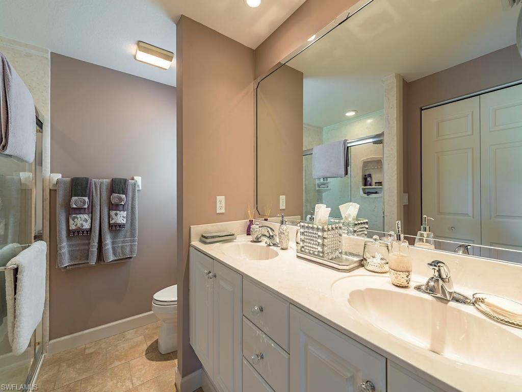 1827 West Crown Pointe Boulevard Naples, FL 34112 - Photo 8 of 12 a bathroom with double vanity sinks a toilet a mirror and shower