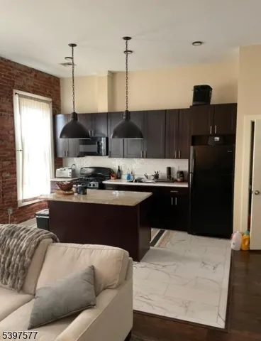a living room with stainless steel appliances kitchen island granite countertop furniture and a wooden floor