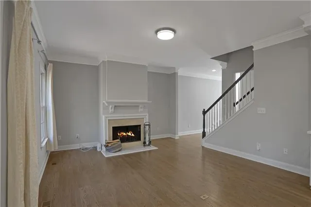 a view of an empty room with wooden floor fireplace and a window