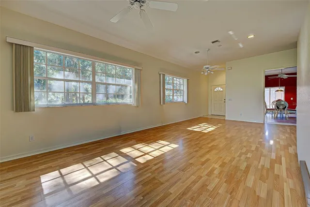 a view of empty room with wooden floor and fan