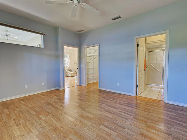 a view of a hallway with wooden floor and a bathroom