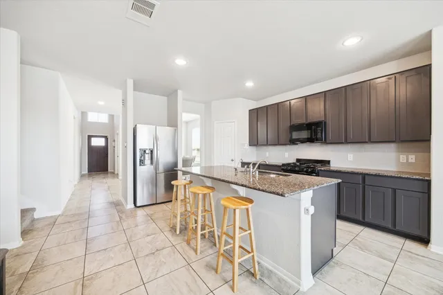 a kitchen with granite countertop a stove a sink dishwasher a refrigerator and cabinets with wooden floor