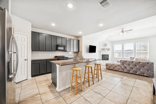 a kitchen with stainless steel appliances granite countertop a stove top oven a sink a dining table and chairs