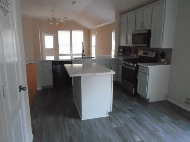 a kitchen with stainless steel appliances granite countertop a stove top oven a sink and a microwave