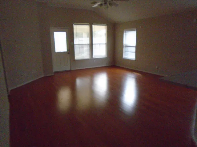 an empty room with wooden floor and windows