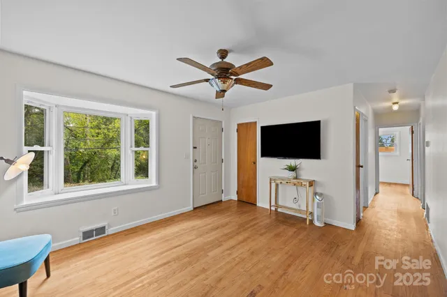 a view of a livingroom with a flat screen tv wooden floor and a ceiling fan