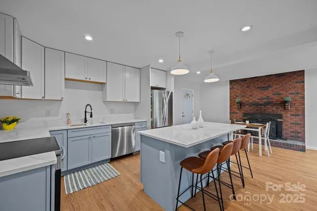 a kitchen with stainless steel appliances granite countertop a table chairs sink and white cabinets