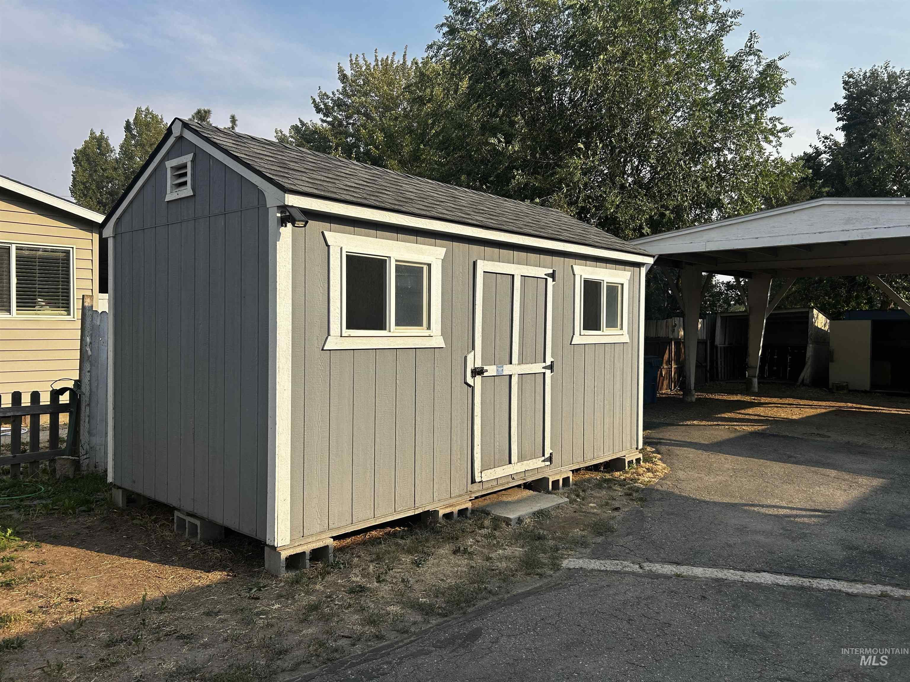 Gable roof shed featuring horizontal siding, two windows, and a single entry door