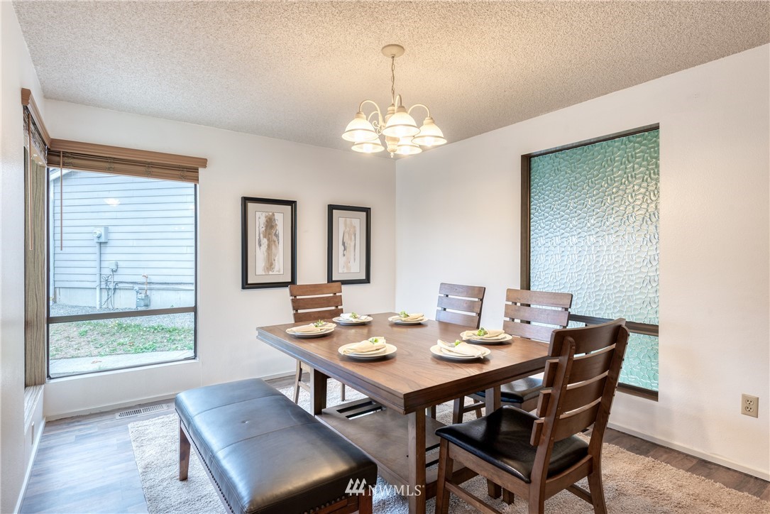 12216 Southeast 258 Place Kent, WA 98030 - Photo 10 of 40 a dining room with wooden floor a chandelier a wooden table and chairs