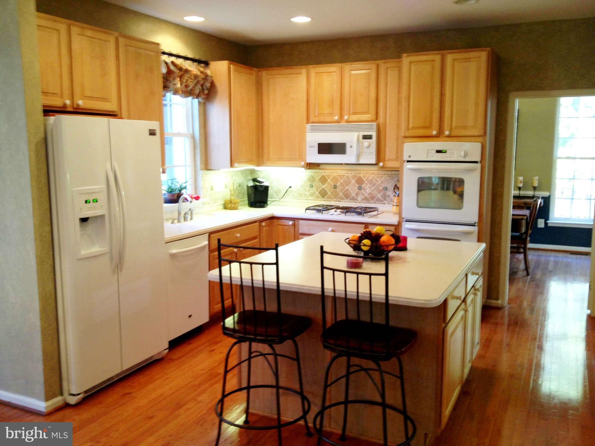 24904 Frederick Road Clarksburg, MD 20871 - Photo 13 of 30 a kitchen with stainless steel appliances granite countertop a refrigerator a sink dishwasher and white cabinets with wooden floor