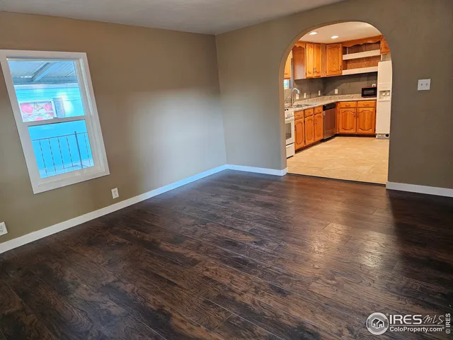 an empty room with wooden floor cabinet and windows