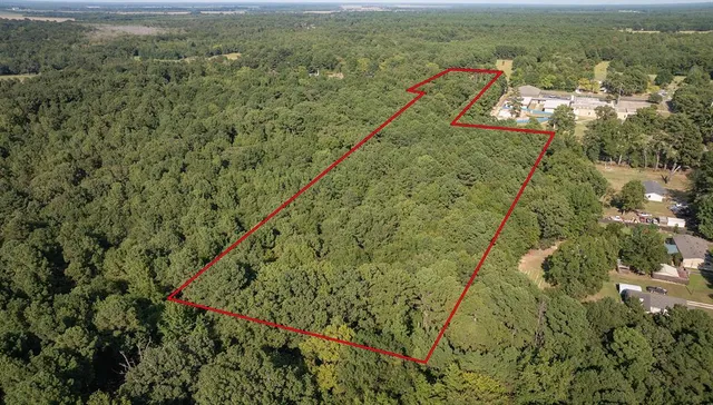 an aerial view of residential house with outdoor space and trees all around