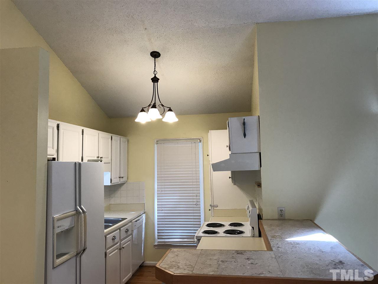 4114 Olde Coach Road Durham, NC 27707 - Photo 7 of 16 a kitchen with stainless steel appliances granite countertop a refrigerator a oven and white cabinets with wooden floor