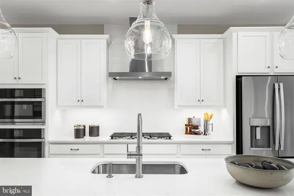 a kitchen with stainless steel appliances a sink a stove and white cabinets