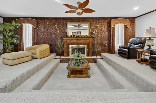 a living room with furniture ceiling fan and a large window