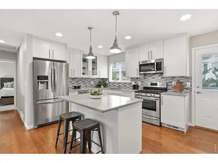 a kitchen with kitchen island a refrigerator a stove a sink and white cabinets