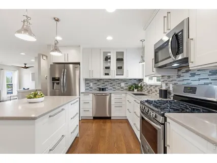 a kitchen with stainless steel appliances kitchen island granite countertop a sink a stove a refrigerator cabinets and chairs