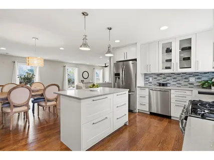 a kitchen with stainless steel appliances kitchen island granite countertop a table chairs and a refrigerator