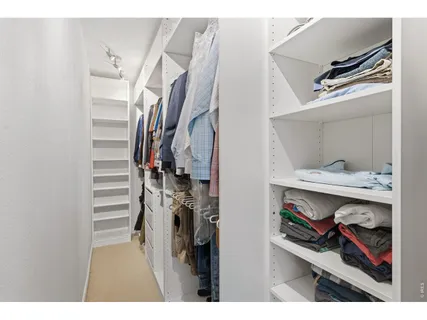 a view of walk in closet with clothes and shoes