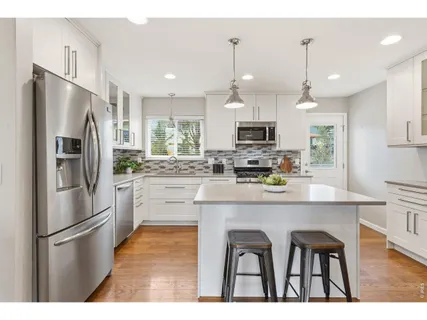 a kitchen with kitchen island granite countertop a refrigerator stove microwave and white cabinets