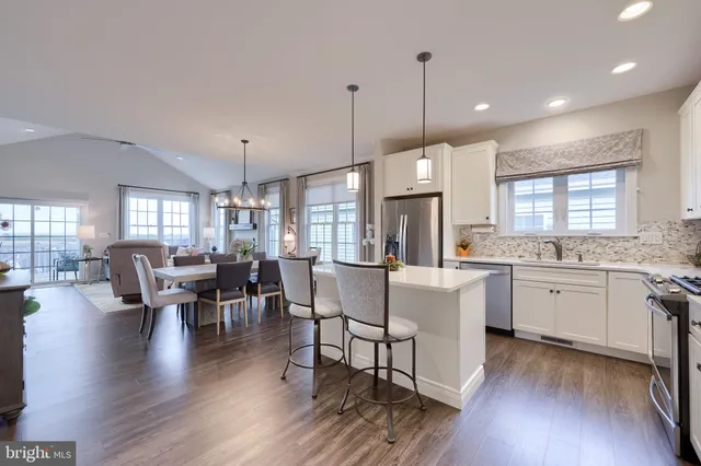 a kitchen with stainless steel appliances granite countertop a refrigerator a oven a sink dishwasher and white cabinets with wooden floor