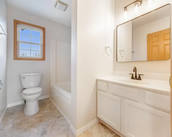 a bathroom with a toilet sink vanity and mirror
