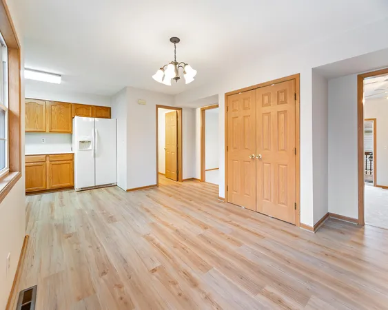 an empty room with wooden floor closet and windows