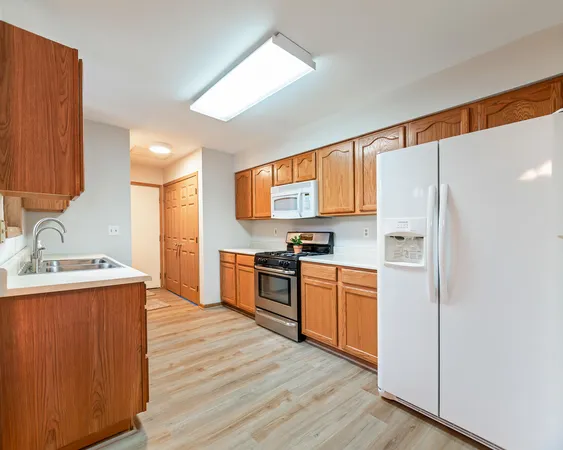 a kitchen with stainless steel appliances granite countertop a refrigerator a sink dishwasher a stove with wooden cabinets and wooden floor