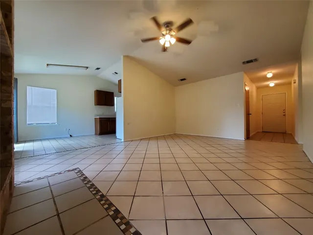 a view of an empty room and chandelier fan