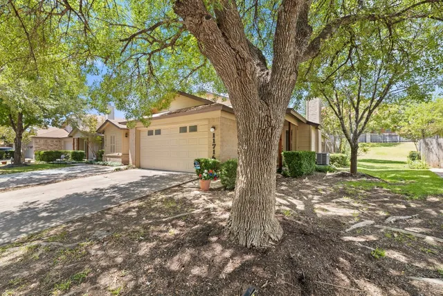 a front view of a house with a yard and large trees