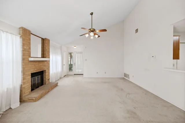 a view of a livingroom with a fireplace a chandelier fan and windows
