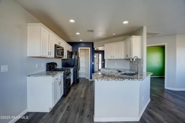 a kitchen with stainless steel appliances granite countertop a stove top oven a sink and a refrigerator