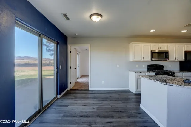 a kitchen with stainless steel appliances granite countertop a refrigerator a stove top oven a sink and dishwasher with wooden floor