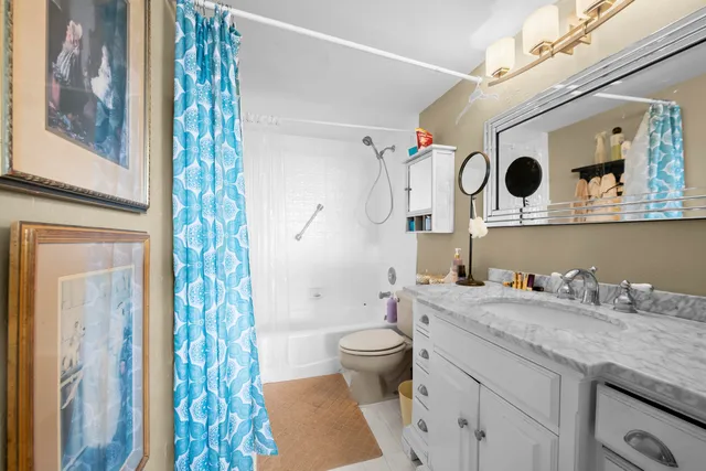 a bathroom with a granite countertop sink a toilet and a shower curtain