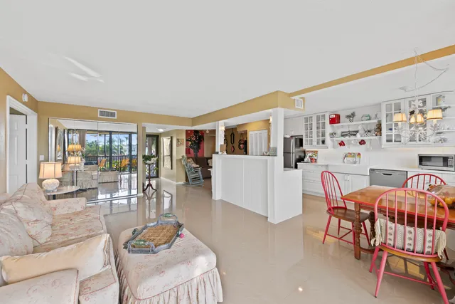 a living room with furniture and a dining table with floor to ceiling window