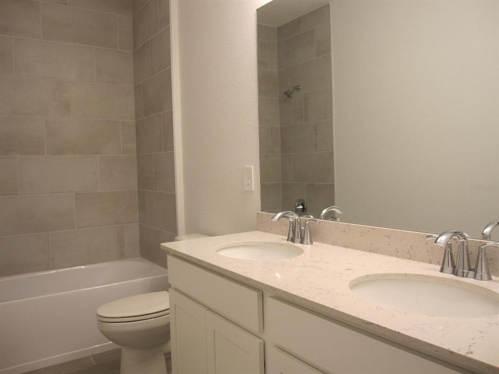 4530 Northwest 14th Loop Ocala, FL 34482 - Photo 33 of 40 a bathroom with a granite countertop sink a toilet and a bathtub