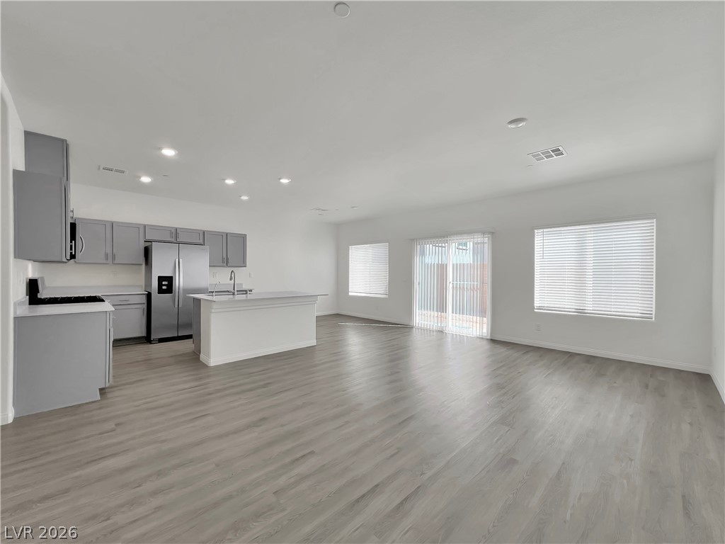 9984 Indigo Cliffs Street Las Vegas, NV 89141 - Photo 30 of 31 Kitchen featuring visible vents, gray cabinets, open floor plan, stainless steel fridge, and light countertops