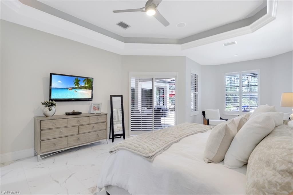 7323 Acorn Way Naples, FL 34119 - Photo 12 of 21 Bedroom with a tray ceiling, a ceiling fan