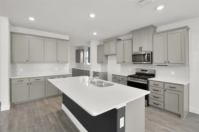 a kitchen with white cabinets sink and stove