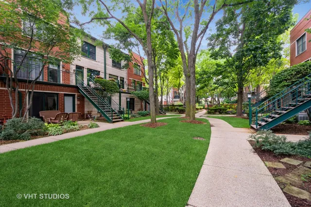 a view of a brick building next to a big yard and large trees