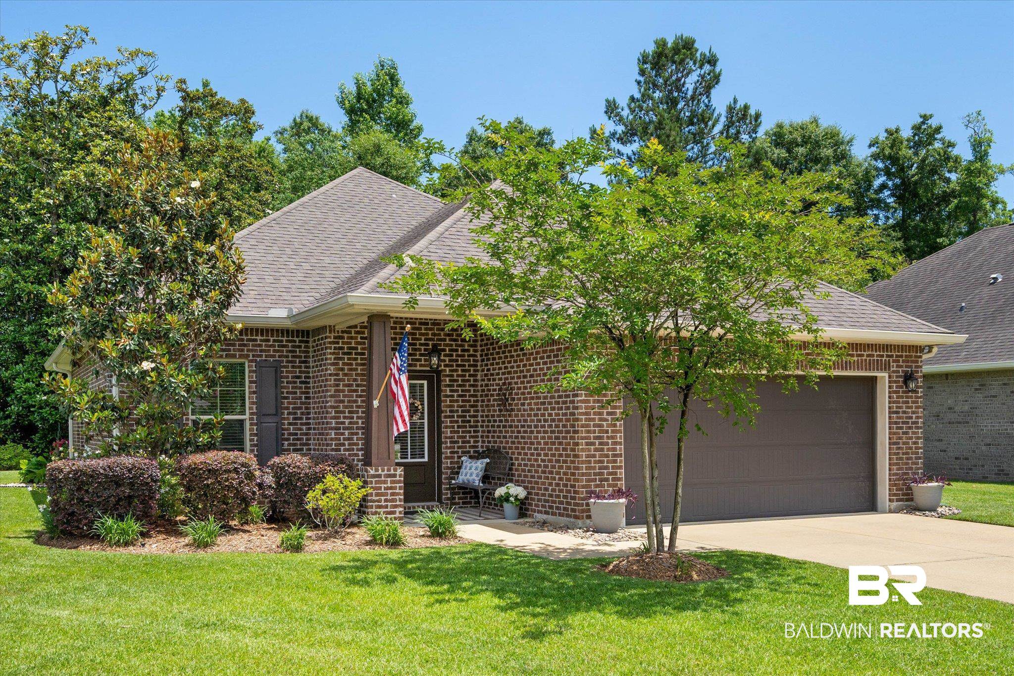 1270 Surrey Loop Foley, AL 36535 - Photo 1 of 27 Traditional brick exterior featuring a covered entry, attached garage, gabled roofline, and established landscaping with mature trees and shrubs