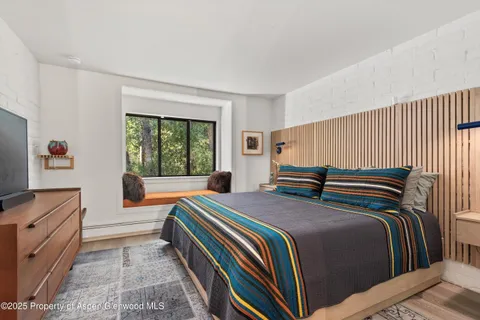 a bedroom with a bed and a dresser next to a window