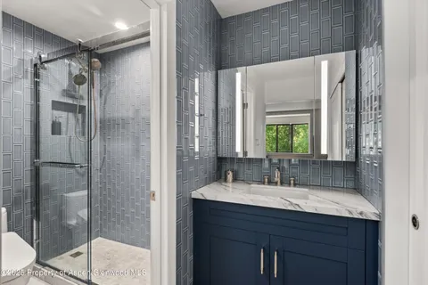 a bathroom with a shower sink vanity mirror and toilet