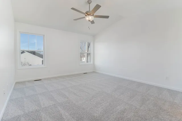 an empty room with windows and fan