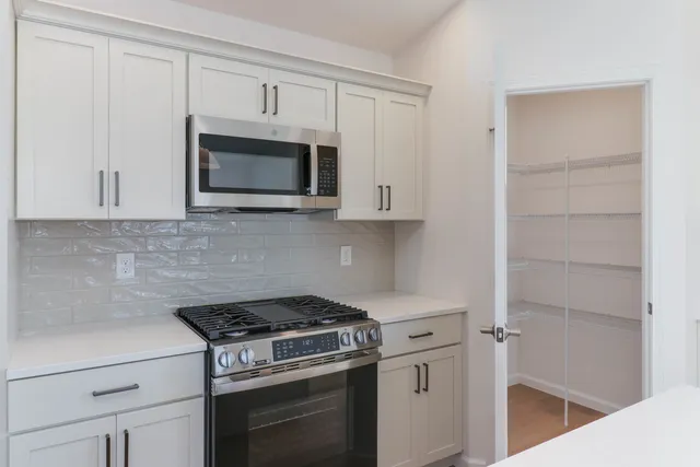 a kitchen with white cabinets and stainless steel appliances