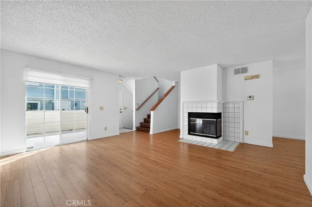 a view of empty room with wooden floor and fireplace